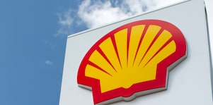 Bel Pilon na katerem se nahaja rdeče-rumen Shellov logotip in v ozadju modro nebo in bel oblak