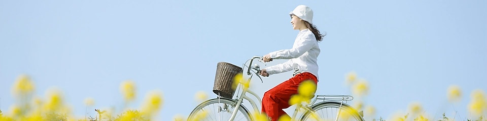 Mlada ženska se poleti s kolesom pelje čez polje.