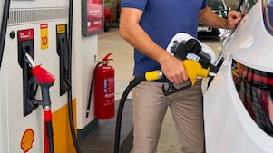 Oseba toči gorivo v bel avtomobil na bencinski črpalki Shell z rumeno točilno ročko. Vidni sta še rdeča in črna ročka z oznakami »Shell V-Power« in »Shell FuelSave Diesel«.