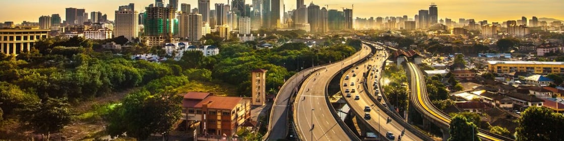 Veliko mesto z visokimi zradbami prikazano iz oddaljene perspektive, v katero pelje široka cesta.