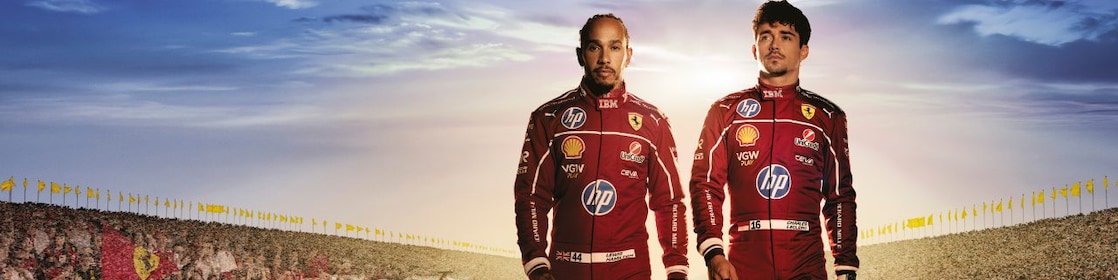 Lewis Hamilton in Charles Leclerc hodita po dirkališču v rdečih oblekah ob sončnem zahodu.