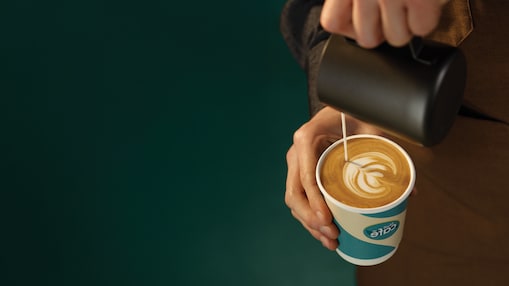 Človek, ki vliva mleko v Shell Cafe kavo