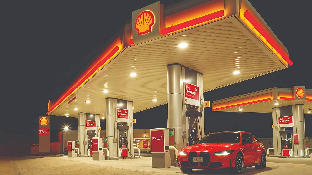 Rdeč BMW avtomobil parkiran pred Shell bencinskim servisom